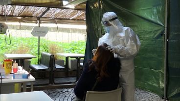 Health worker wearing sanitary suit performing nose swab