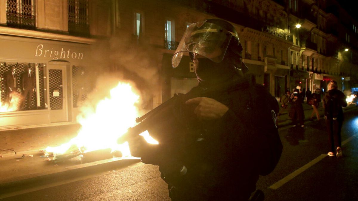 Francia rendőr egy égő barikád mellett Párizsban, 2020. november 24-én