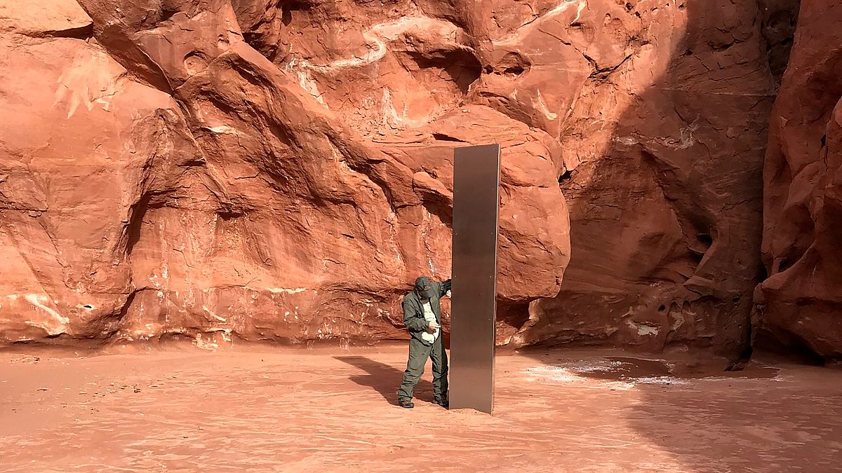 A state worker inspects a metal monolith found in a remote area in Utah