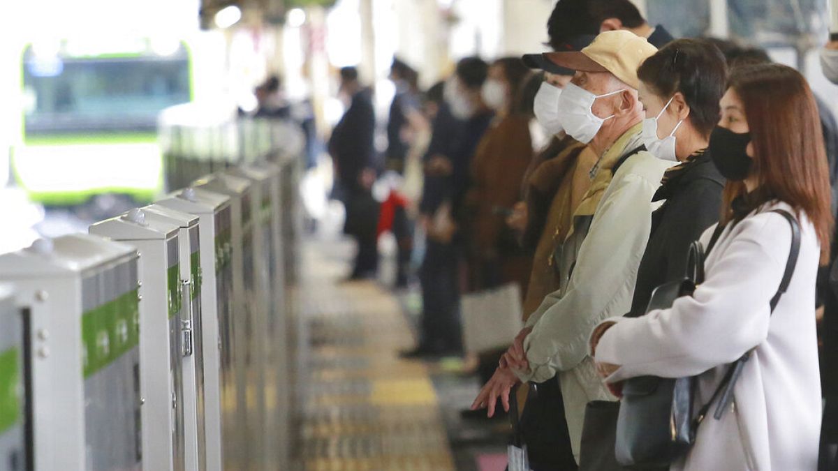 People wearing face masks to protect against the spread of the coronavirus wait for train at a station in Tokyo