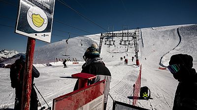 People wearing protective face masks queue up to use ski lifts, on the opening day of the Les 2 Alpes French resort on October 17