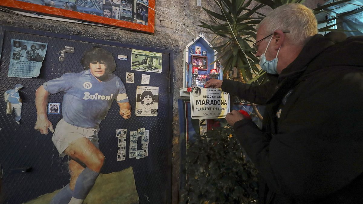 A man in front of a makeshift shrine of soccer legend and former Napoli player Diego Armando Maradona, pays his homage to the late soccer legend, in Naples. 