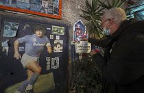 A man in front of a makeshift shrine of soccer legend and former Napoli player Diego Armando Maradona, pays his homage to the late soccer legend, in Naples.