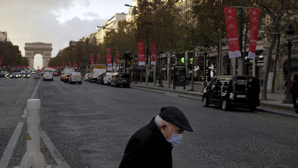 An elderly man wears a face mask as he walks on the Champs Elysee avenue, in Paris, Thursday, Nov. 19, 2020. 
