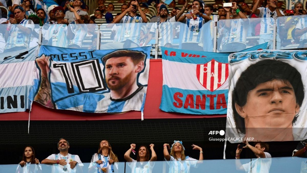 صورة من الارشيف- مشجعو الأرجنتين، ملصقات الأولى تحمل صورة  ليونيل ميسي والثانية صورة دييغو مارادونا 