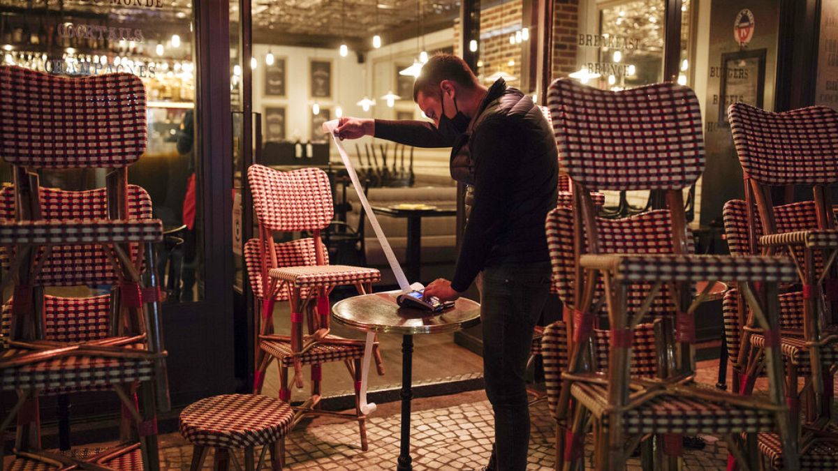 A waiter checks the final revenue as he closes a bar terrace in Paris, Saturday, Oct. 17