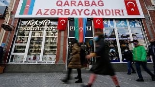 People walk past a poster reading "Karabakh is Azerbaijan" in Ganja, Azerbaijan's second largest city, near the border with Armenia, Azerbaijan, Thursday, Nov. 26, 2020.