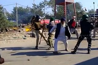 Police officers using batons on farmers as they run away