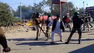 Police officers using batons on farmers as they run away