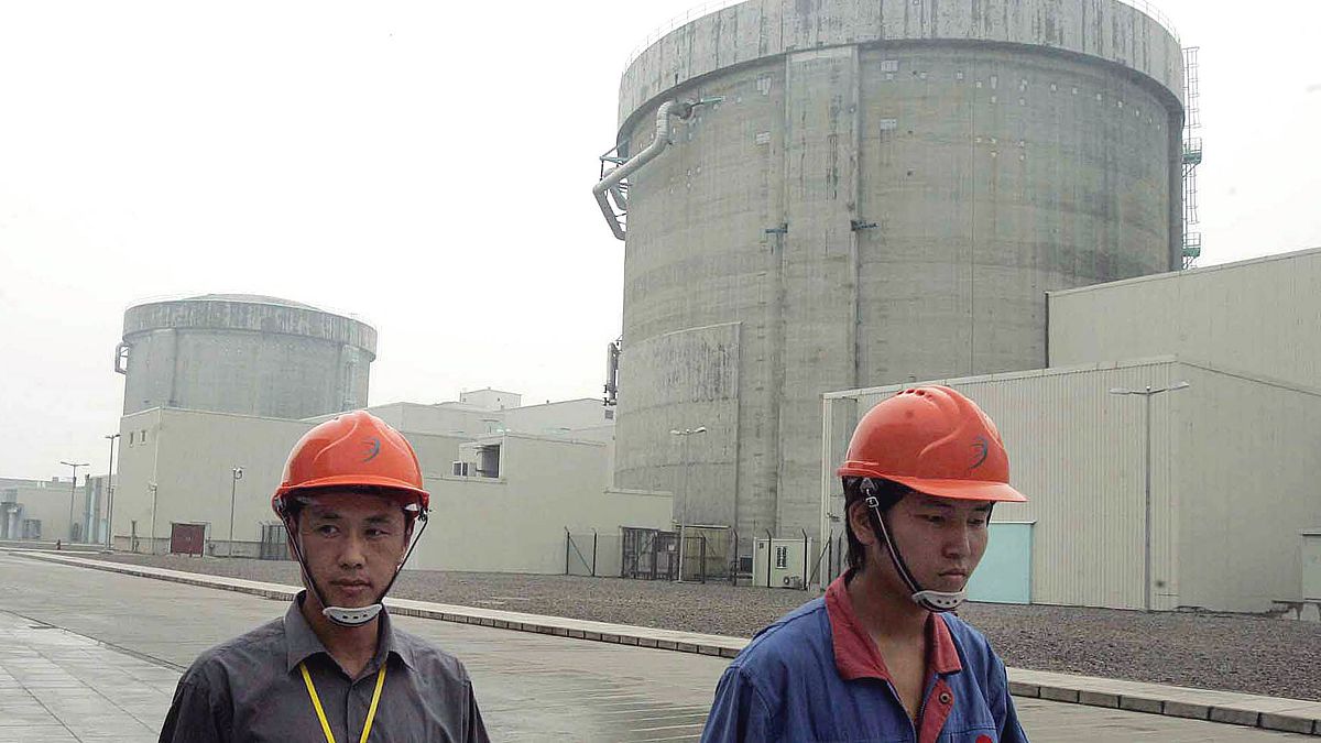workers walk past a part of the Qinshan No. 2 Nuclear Power Plant, China's first self-designed and self-built national commercial nuclear power plant in Qinshan