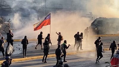Protester holding Chilean flag march clashes with police