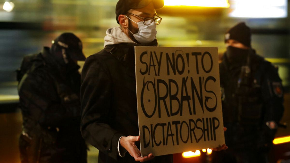 Egy tüntető Orbán-ellenes táblával Varsóban 2020. november 30-án