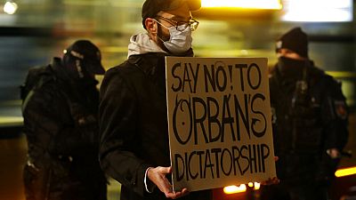 Egy tüntető Orbán-ellenes táblával Varsóban 2020. november 30-án