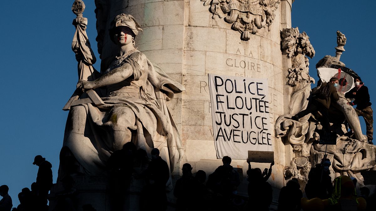 A banner reading " Police, blurring, justice blind" is seen on the statue in the Place de la Republique in ¨Paris, November 28, 2020.