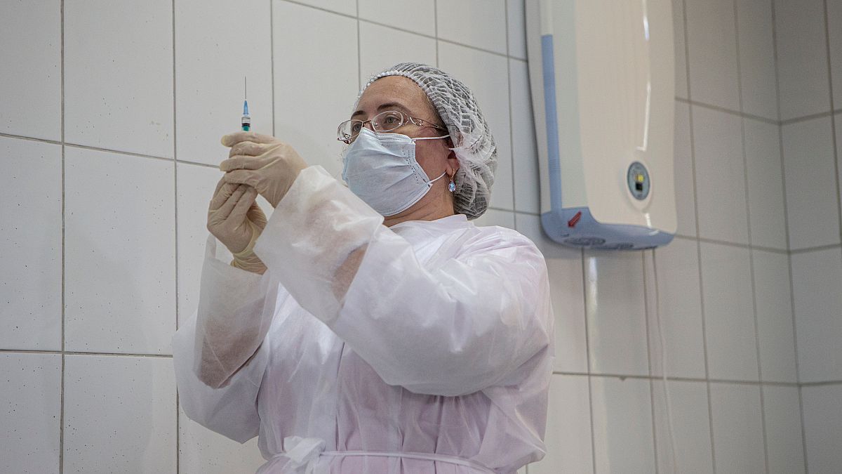 Orosz egészségügyi dolgozó készül a Sputnik V oltás beadására egy tesztalanynak