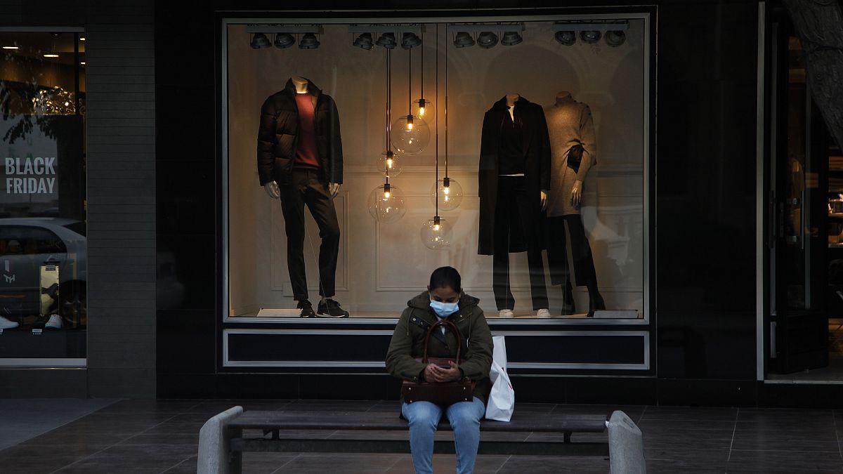 A woman wearing face mask sits on a bench at a main shopping street in capital Nicosia