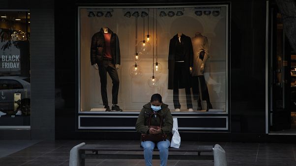 A woman wearing face mask sits on a bench at a main shopping street in capital Nicosia