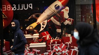 Un hombre con mascarilla pasa ante un escaparate con decoración navideña en Bruselas, Bélgica