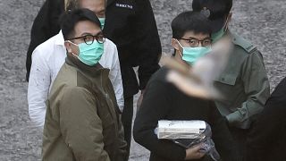 Hong Kong activists Joshua Wong, right, and Ivan Lam, left, are escorted by Correctional Services officers to get on a prison van