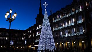 Pedestrians are silhouetted in front of a giant Christmas tree at the Plaza Mayor, Madrid, Spain