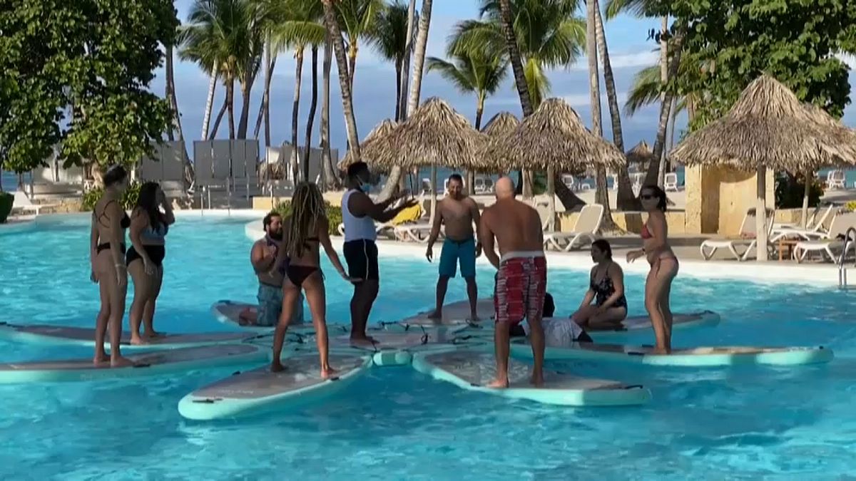 Un grupo de turistas hace ejercicios con un monitor en la piscina de un hotel de la República Dominicana