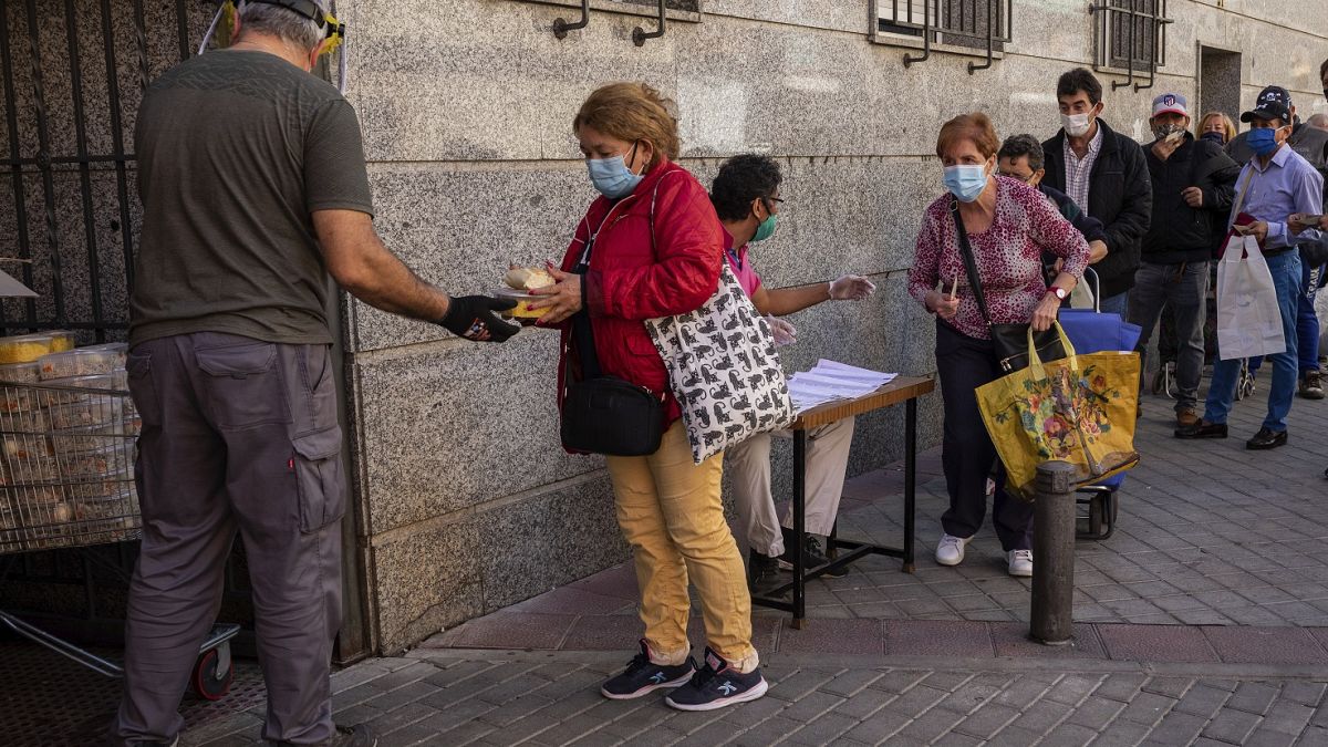 Una cola de personas aguarda para recoger alimentos donados por voluntarios y miembros de una congregación religiosa en Madrid