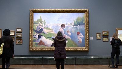 Visitors looking at a Georges Seurat painting