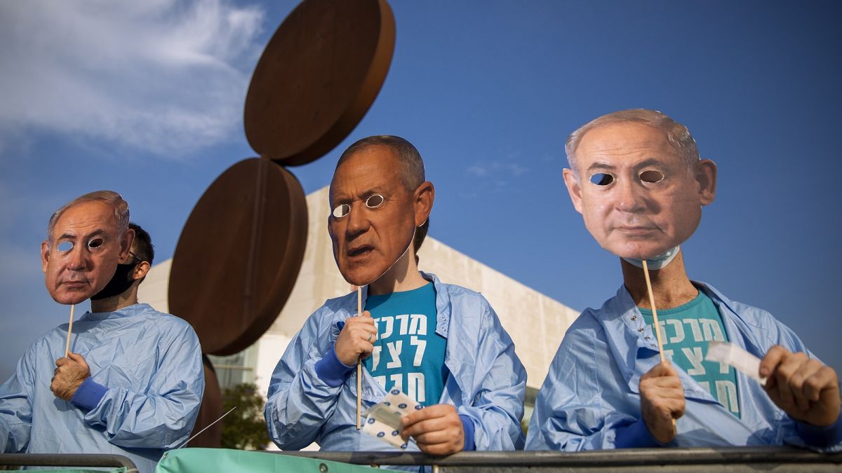 Israeli demonstrators hold masks depicting Benjamin Netanyahu and Benny Gantz during a protest against a vote to dissolve the Knesset.