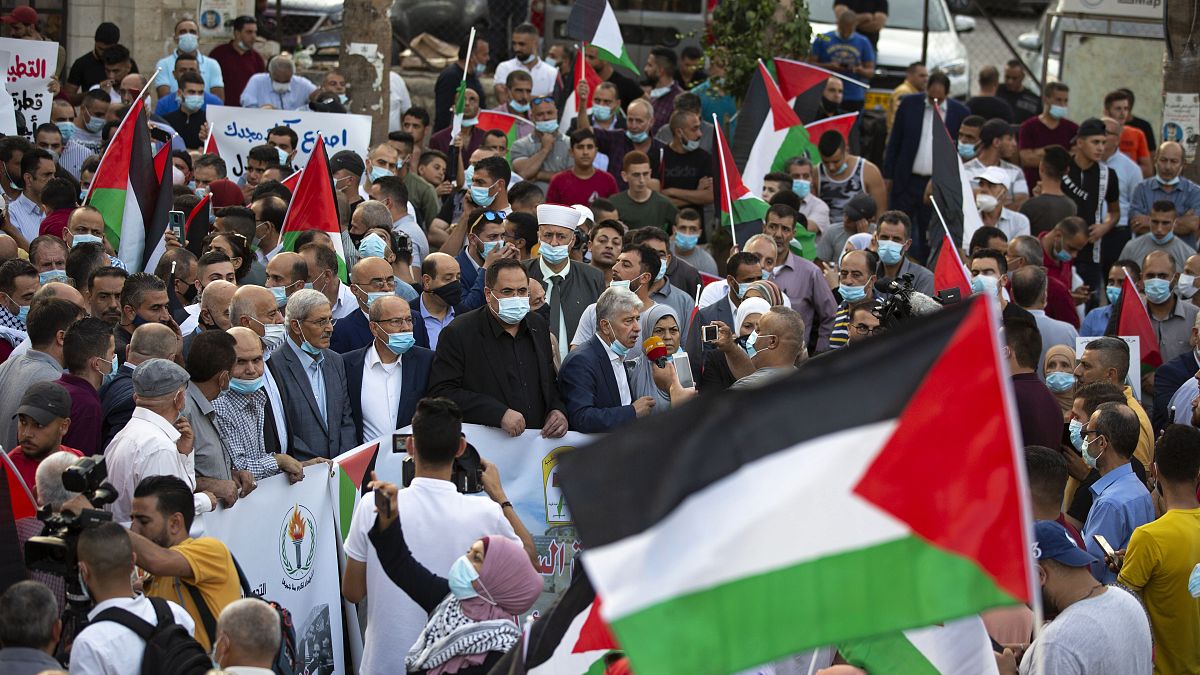 فلسطينيون يلوحون بالأعلام احتجاجاً على تطبيع العلاقات بين الإمارات العربية المتحدة والبحرين مع إسرائيل، رام الله بالضفة الغربية