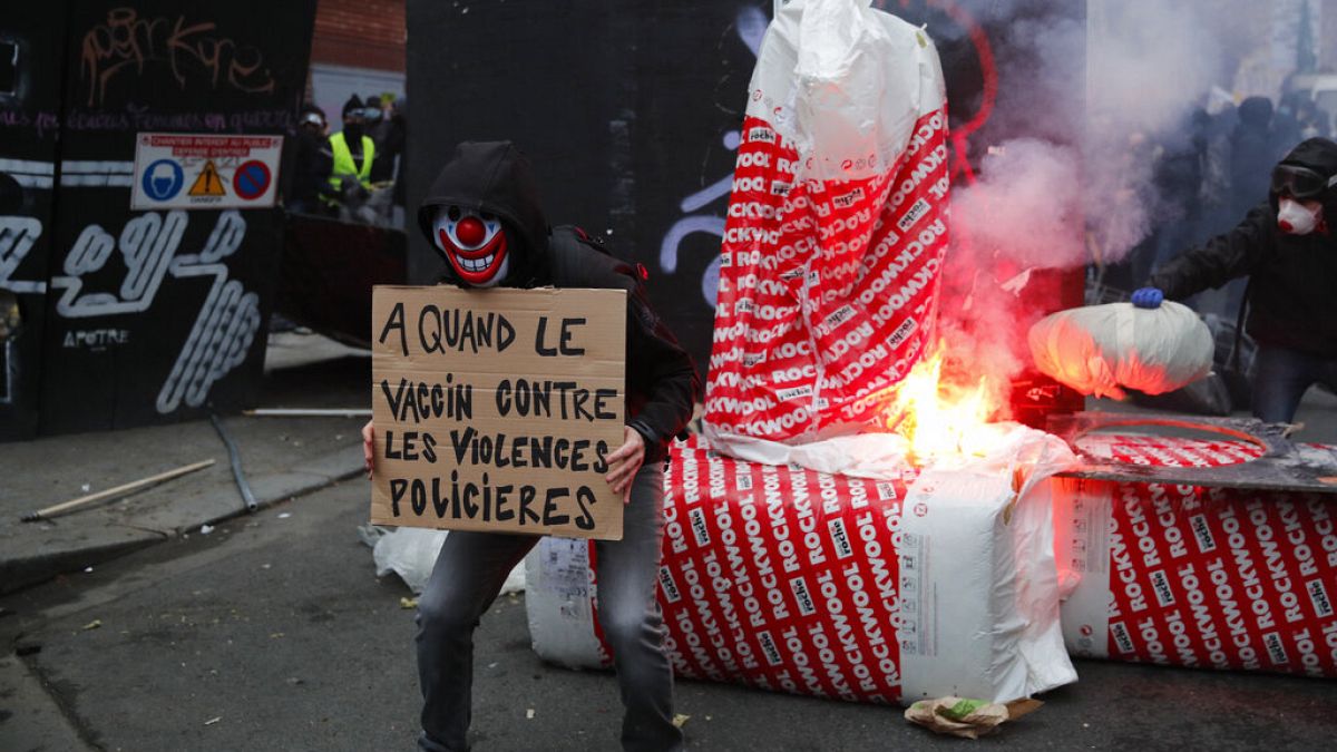 متظاهر يحمل ملصق كتب عليه "لقاح ضد عنف الشرطة" أمام حاجز خلال مظاهرة يوم السبت 5 ديسمبر 2020 في باريس