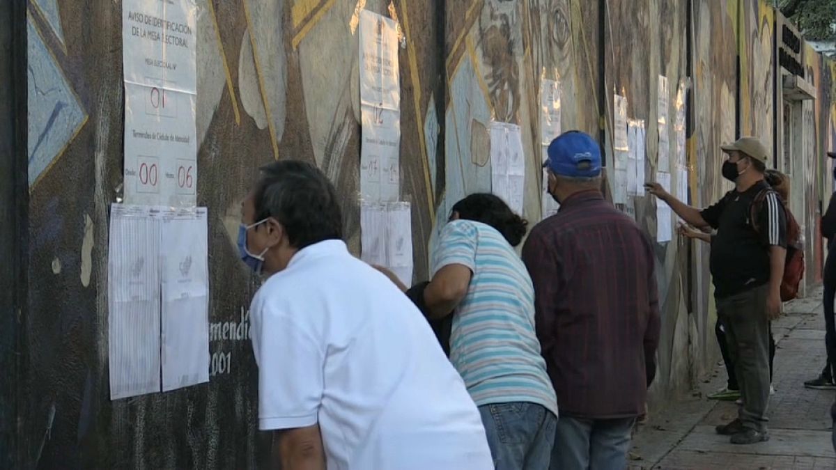 Varios votantes buscan su mesa a su llegada a los centros electorales