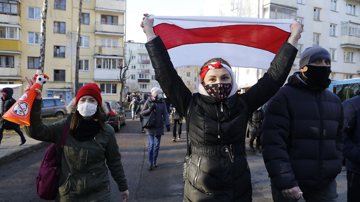 A protester waves an old Belarusian national flag, during an opposition rally against the official presidential election results in Minsk, Belarus, Sunday, Dec. 6, 2020. 