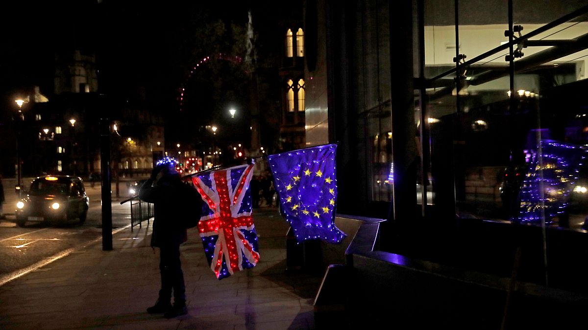 Egy brexitellenes tüntető kivilágított brit és EU-s zászlóval Londonban