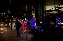 Egy brexitellenes tüntető kivilágított brit és EU-s zászlóval Londonban