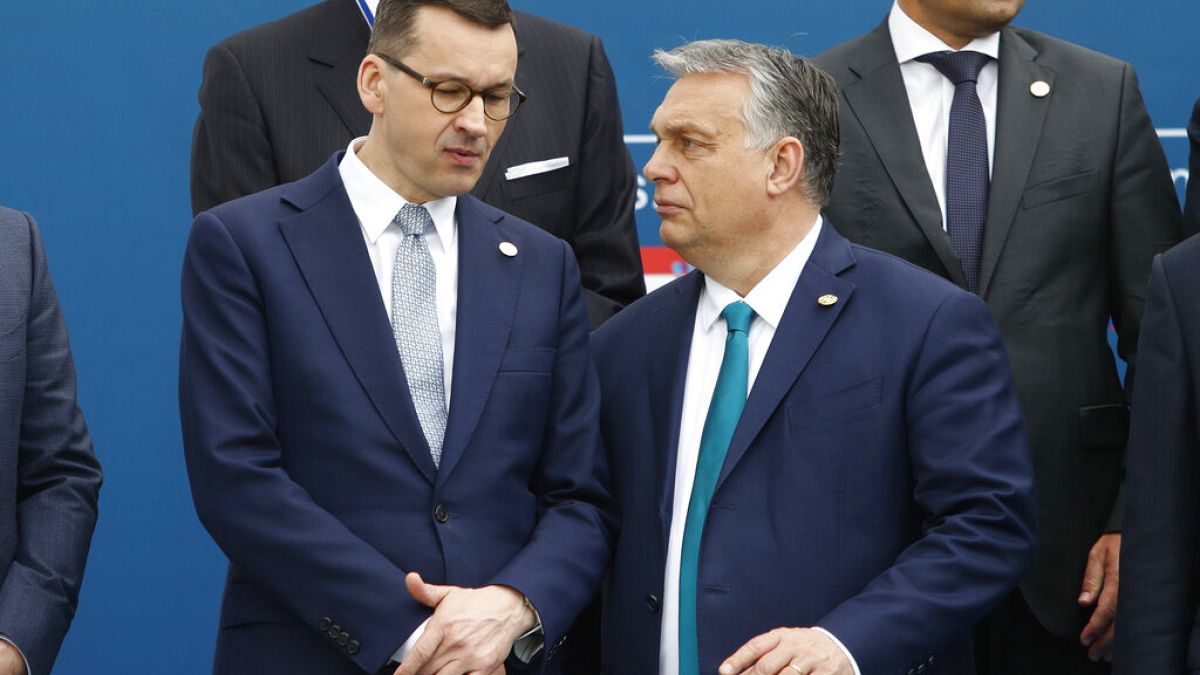 In this Feb. 1, 2020 file photo, Poland's PM Mateusz Morawiecki, left, and Hungary's PM Victor Orban speak as they line up for a group picture prior to a meeting in Beja