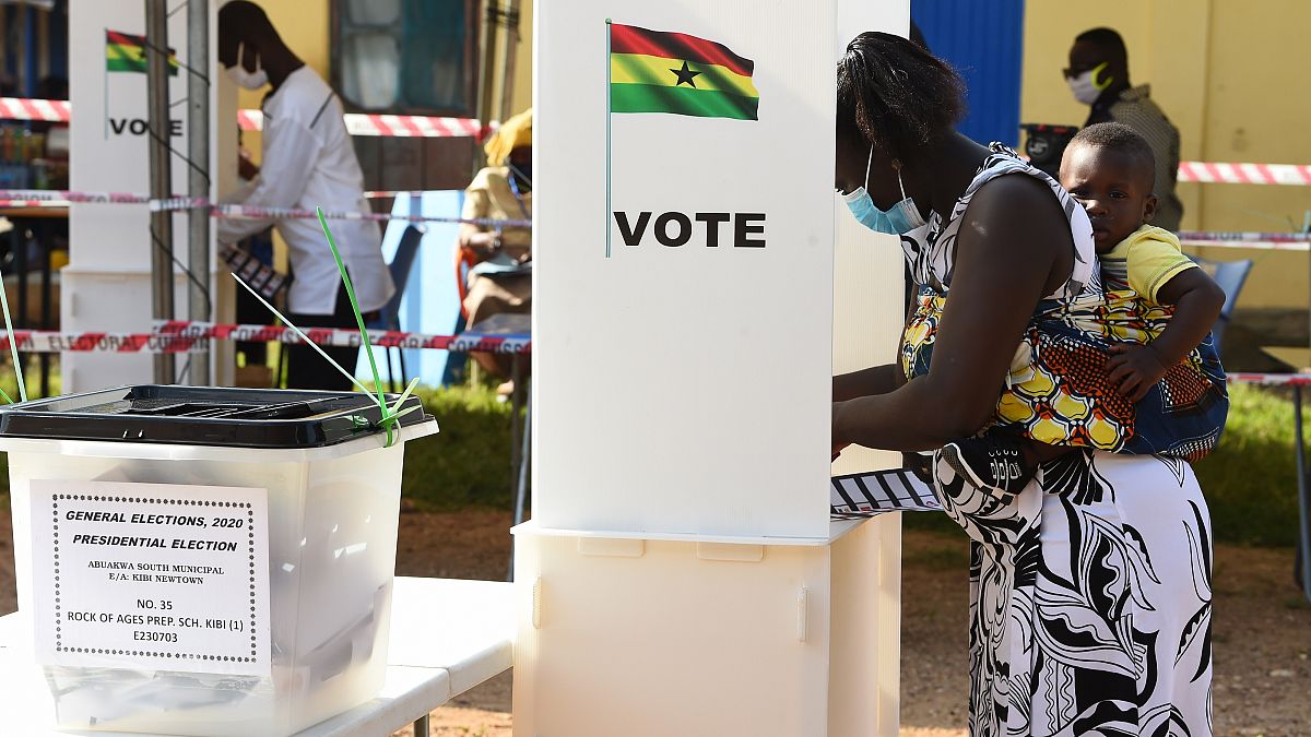 A woman holds her child as she prepares to cast her vote at a polling station in Kyebi during Ghana's presidential and parliamentary elections. 