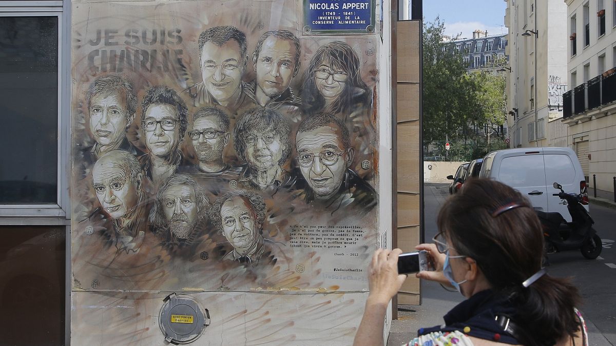 A woman wearing a face mask takes a pictures of a painting by French street artist Christian Guemy, a.k.a. 'C215' in Paris on Wednesday, Sept. 2, 2020.