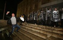 A protester throws a stone to police officers outside the Prime's Minister office during clashes in Tirana, Albania , on Wednesday, Dec. 9, 2020