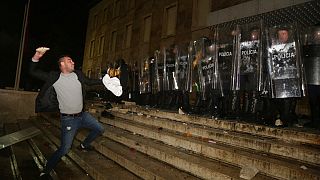 A protester throws a stone to police officers outside the Prime's Minister office during clashes in Tirana, Albania , on Wednesday, Dec. 9, 2020