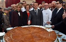 French president Emmanuel Macron (C) and his wife Brigitte (L) cut slices of a traditional epiphany cake during a ceremony at the Elysee palace, on January 12, 2018