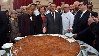 French president Emmanuel Macron (C) and his wife Brigitte (L) cut slices of a traditional epiphany cake during a ceremony at the Elysee palace, on January 12, 2018