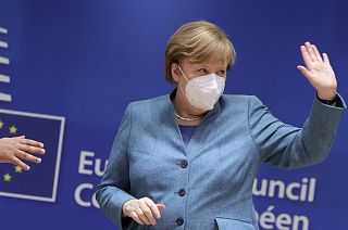 German Chancellor Angela Merkel waves as she attends a round table meeting at an EU summit in Brussels, Thursday, Dec. 10, 2020.