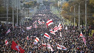 People with old Belarusian national flags march during an opposition rally to protest the official presidential election results in Minsk, Belarus, Sunday, Oct. 18, 2020