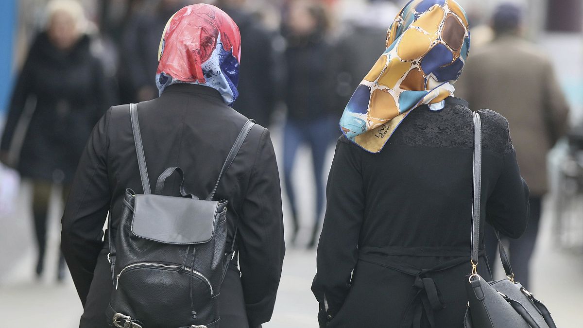 In this photo taken Friday, April 21, 2017 women with headscarfs are walking in a pedestrian zone in Vienna, Austria.
