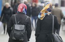 In this photo taken Friday, April 21, 2017 women with headscarfs are walking in a pedestrian zone in Vienna, Austria.