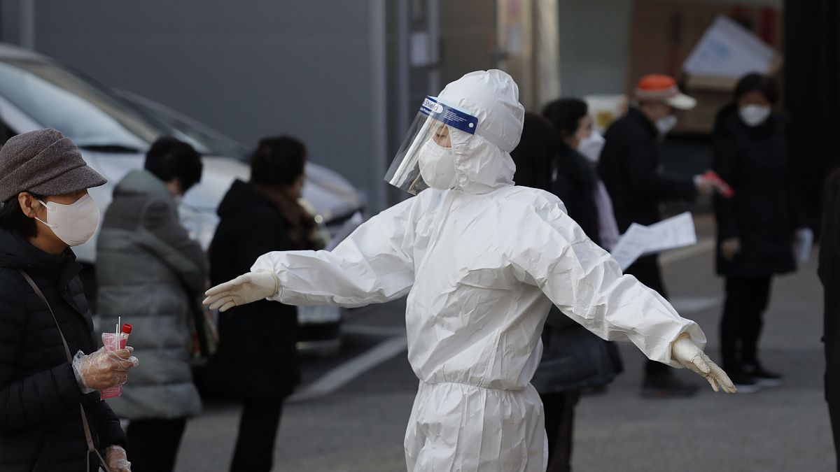 A medical worker wearing protective gear speaks as people wait in queue during testing for COVID-19 at a coronavirus testing centre in Seoul, South Korea.