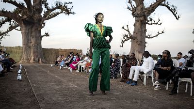 A fashion model poses at the end of the runway during Dakar Fashion Week.