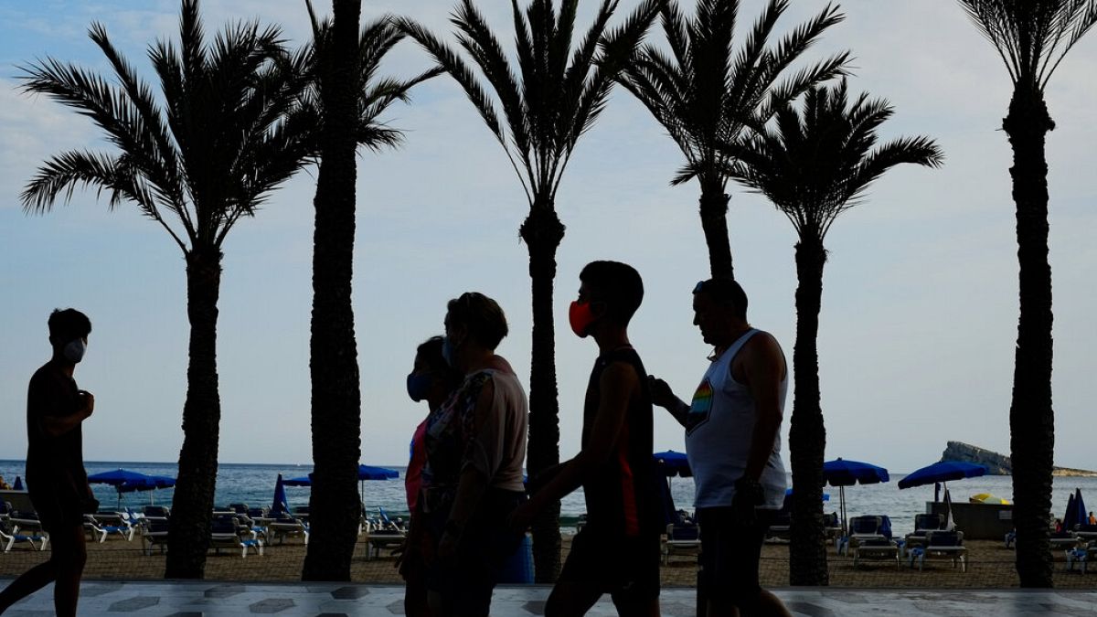Un grupo de turistas, con mascarillas para prevenir la propagación del coronavirus, camina al lado de la playa en Benidorm, en el sudeste de España.