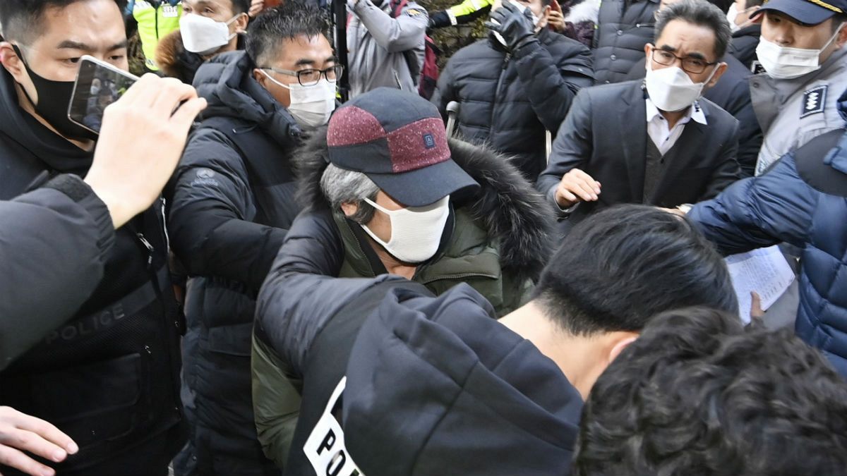 Cho Doo-soon, center, escorted by police officers, arrives home in Ansan, South Korea, Saturday, Dec. 12, 2020. 