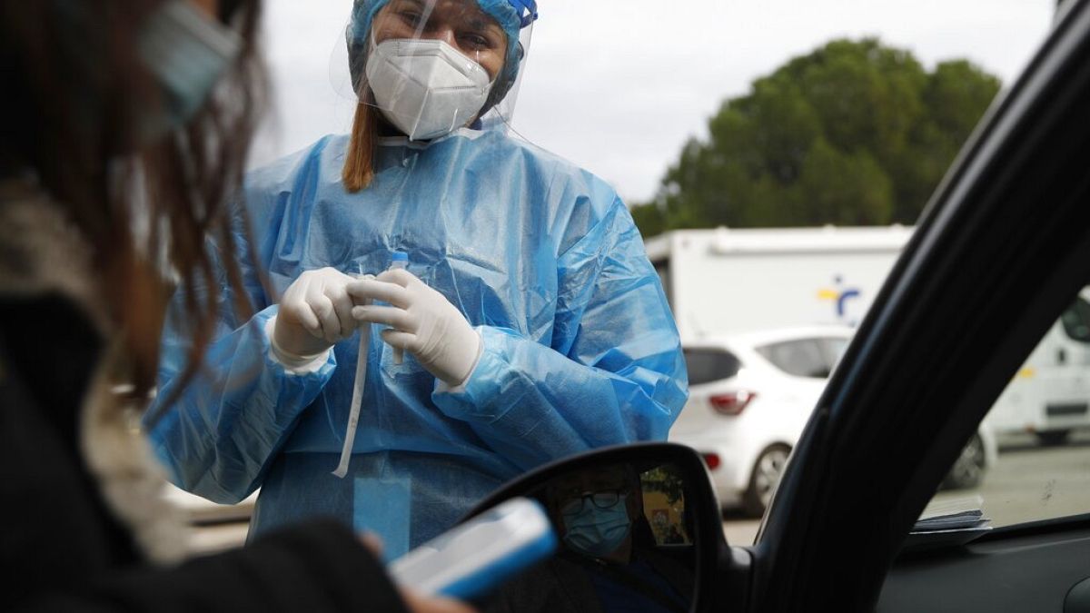 Medical personnel prepares to conduct a COVID-19 rapid test at a drive-through testing site in Athens